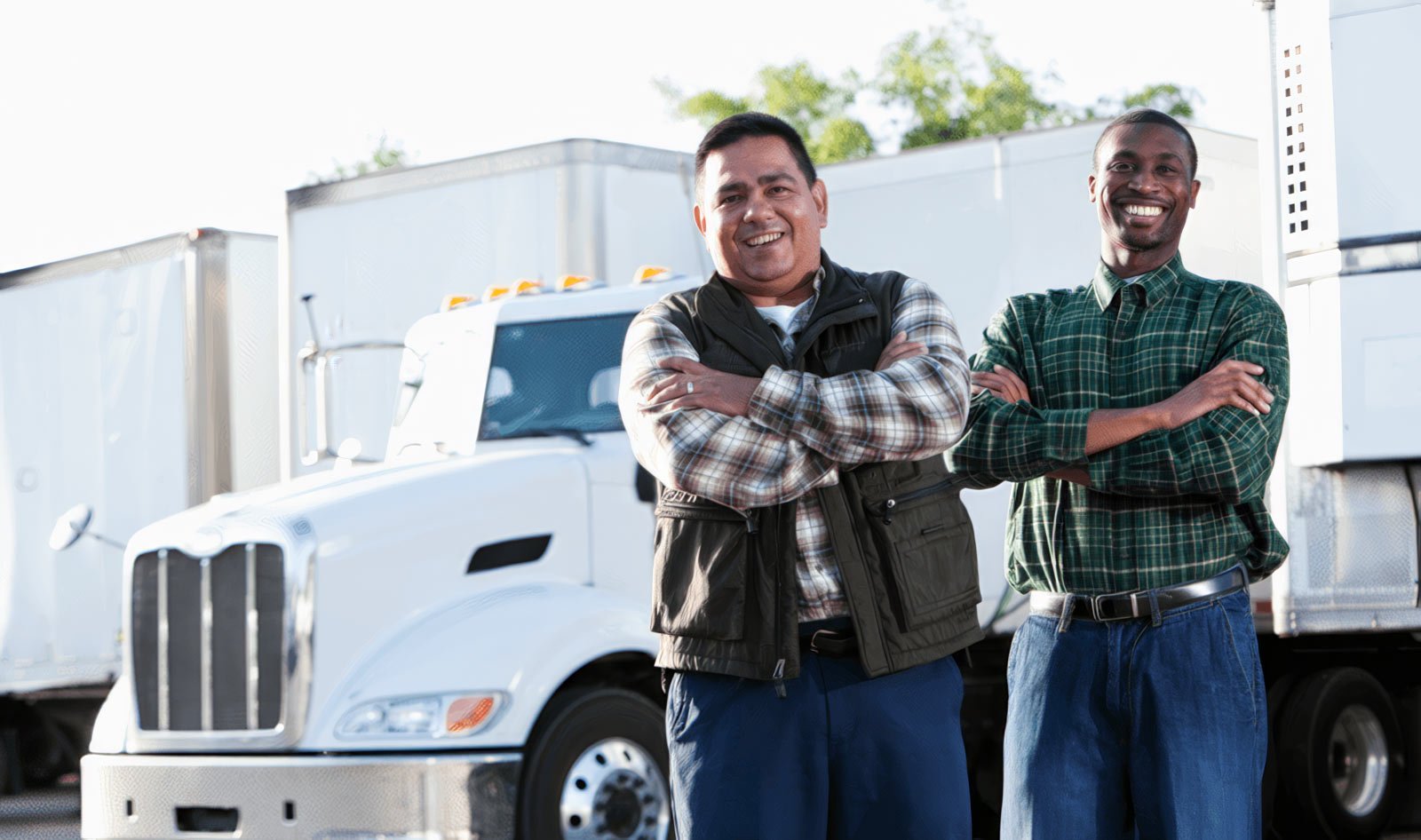 two-men-smiling-in-front-of-trucks